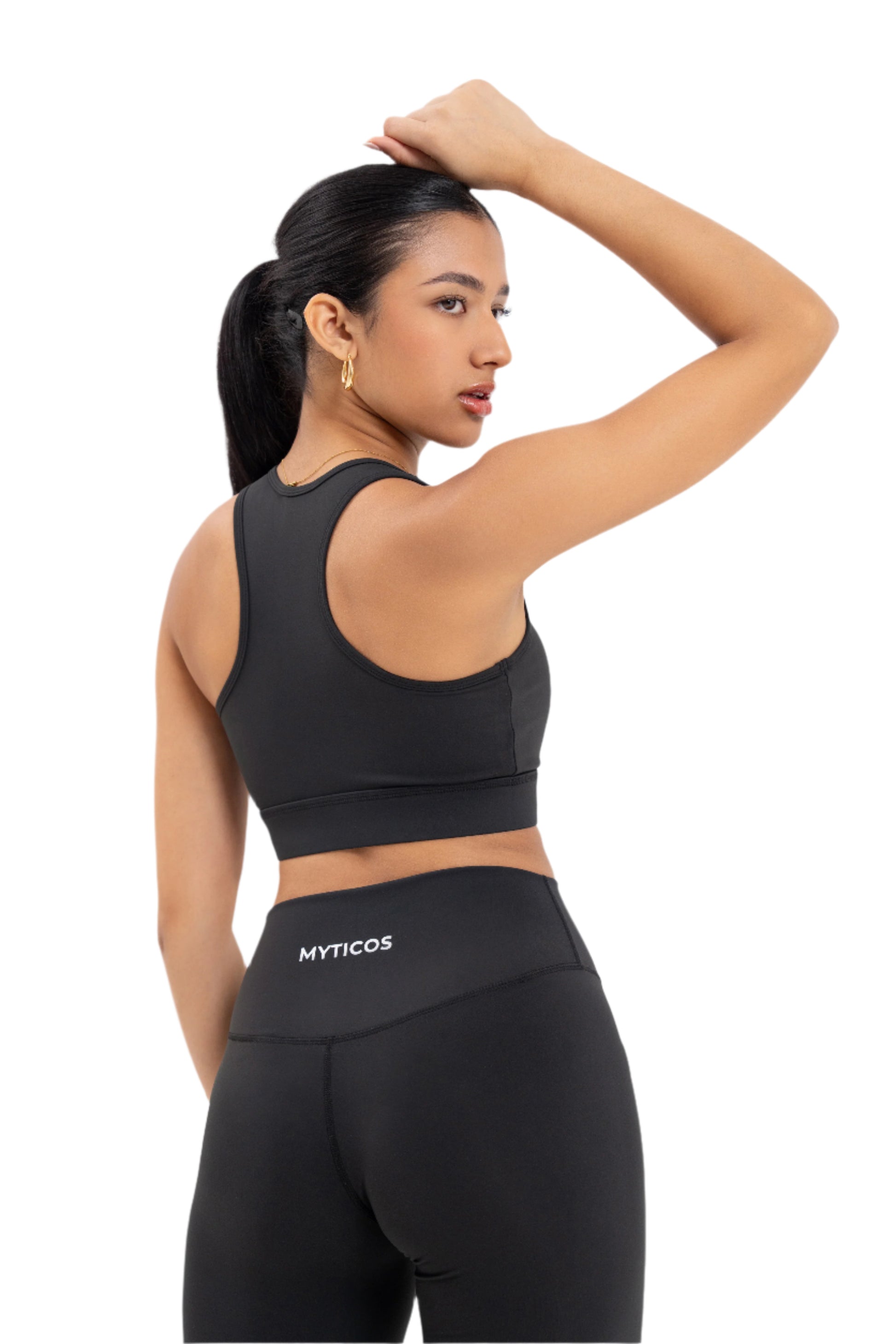 Back view of woman wearing Myticos®️ black sports bra and leggings set, highlighting the logo on the waistband and racerback design of the bra against a white background.