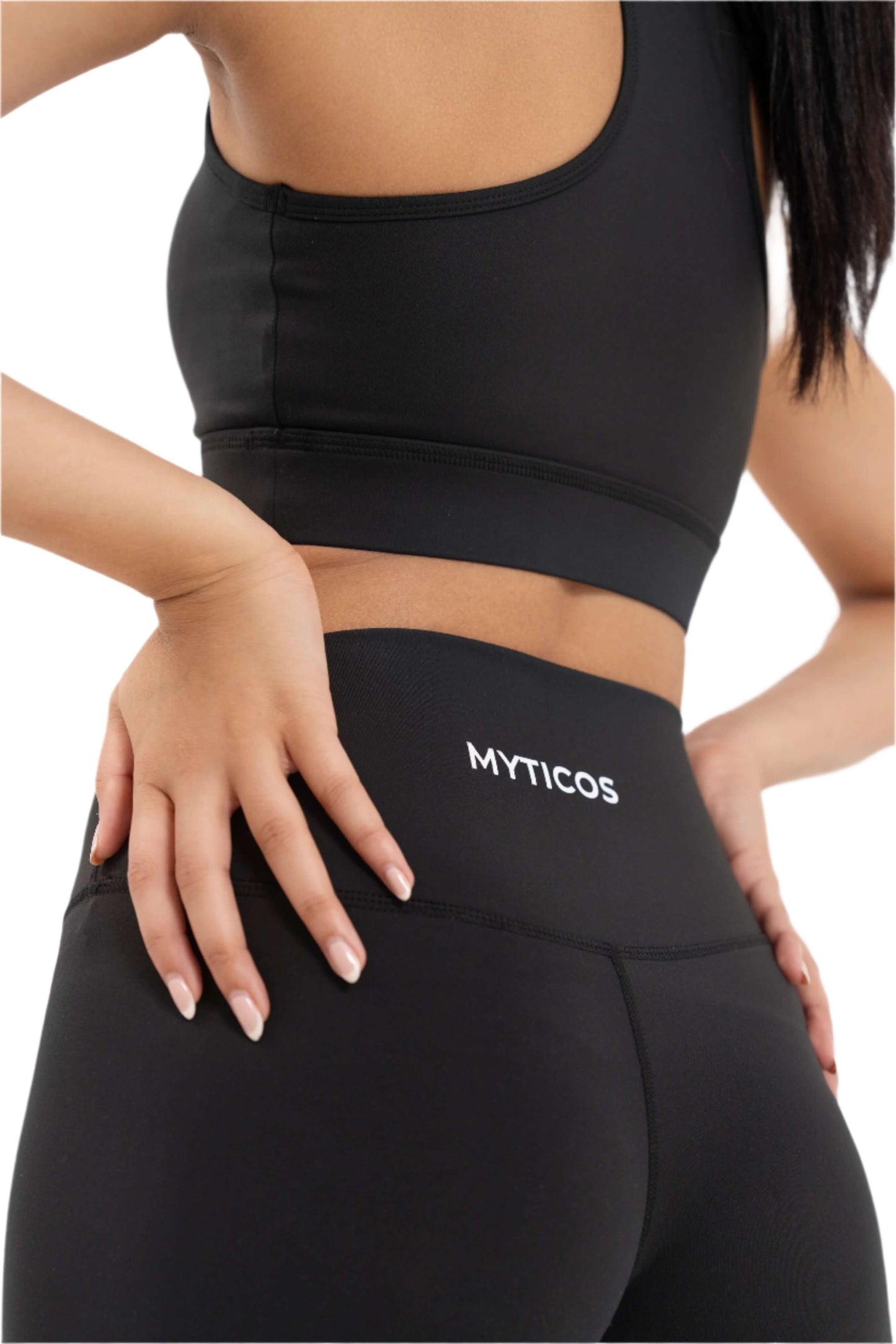 Close-up of Myticos®️ logo on black women's leggings waistband, highlighting stitching, fabric texture, and premium fit against a white background.