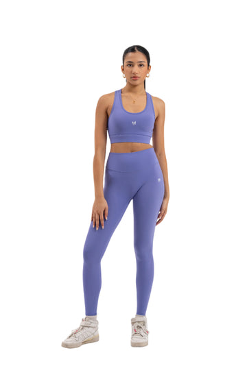 Front view of woman wearing Myticos®️ lavender sports bra and leggings set, showcasing sleek design and supportive fit against a white background.