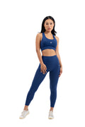 Side view of woman wearing Myticos®️ navy blue sports bra and leggings, highlighting fit and sleek design against a white background.