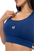 Close-up view of Myticos®️ logo on navy blue women's sports bra, showcasing fabric texture and supportive fit.