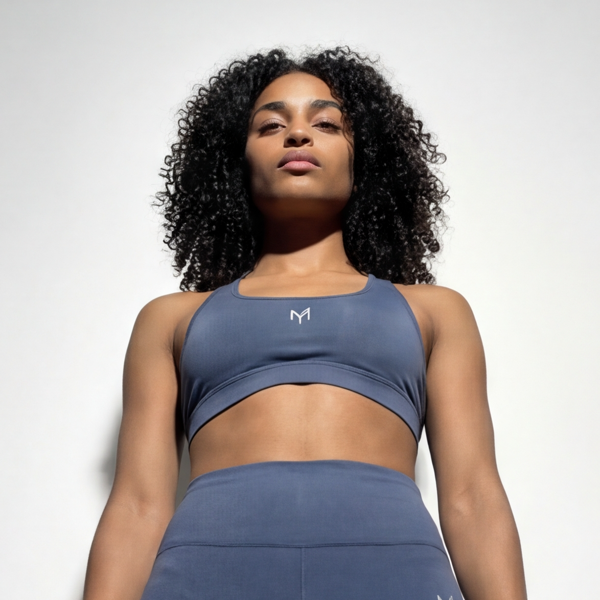 Woman wearing a blue athletic outfit with a logo on a light gray background