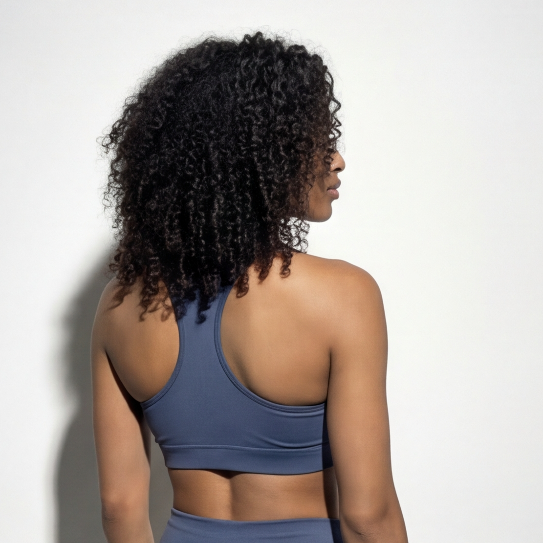 Woman wearing a blue sports bra and leggings against a white background