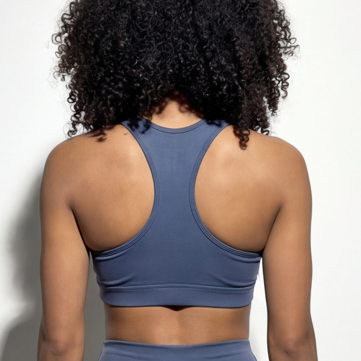 Person wearing a blue sports bra and leggings on a plain background
